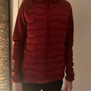 Röd jacka från Peak Performance - Säljer en snygg röd jacka från Peak Performance. Jackan har en quiltad design med dragkedja framtill och långa ärmar. Perfekt för kyligare dagar med sin stilrena look och bekväma passform.