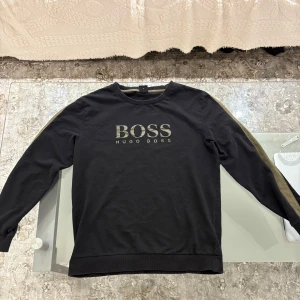 Boss tröja  - Beskrivning: Säljer en Hugo Boss-tröja i storlek M. Tröjan är i bra skick (6/10) med endast mindre tecken på användning. Det enda är att en del av texten på B har slitits bort mycket lite, men det syns knappt. Färgen har blivit lite värre.  