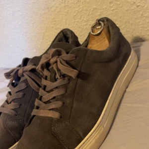 Gråa sneakers från Vagabon - Snygga gråa sneakers från Vagabond i mocka med klassisk snörning. Perfekta för en stilren look med en bekväm sula.                                                                       Pris går att diskuteras.                                                        Dem är rätt bra skick men slitet i hälen