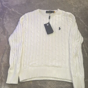 Vit stickad tröja från Ralph Lauren - Säljer en stilren vit stickad tröja från Ralph Lauren med klassiskt kabelstickat mönster. Tröjan har långa ärmar och en liten broderad logotyp på bröstet. Perfekt för en elegant och avslappnad look. Aldrig använd passar storlek Xs och S, pris kan alltid diskuteras och extra bilder finns alltid