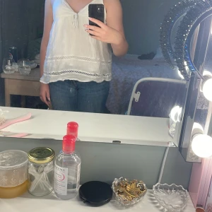 Vit linnetopp från Gina Tricot - Supersöt vit linnetopp från Gina Tricot med tunna axelband och v-ringning. Toppen har knyt fram och fina spetsdetaljer längs nederkanten. Luftig och lätt, perfekt för varma dagar. Passar dig som gillar en avslappnad och feminin stil.