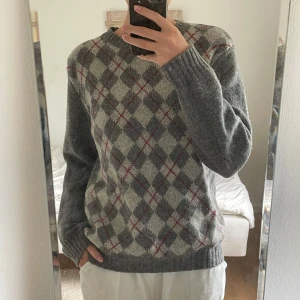 Grå rutig stickad tröja Benetton - Säljer en klassisk ”farfars” stickad tröja från Benetton! Passar till alla årstider. Har ett litet hål som sytts vid armbågen