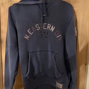 Blå hoodie från Polo RL med tryck - Säljer en blå hoodie från Polo Ralph lauren. Tröjan har huva med snörning, känguruficka och långa ärmar. Perfekt för dig som gillar en avslappnad stil. Super skön och inga hål osv. Bara att höra av er om ni vill veta något ytterligare, vid snabb affär kan jag sänka priset!