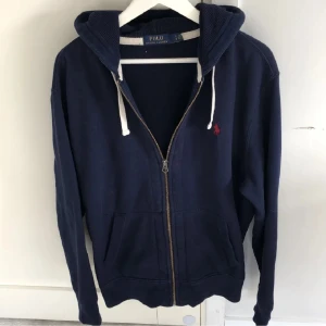 Marinblå hoodie från Polo Ralph Lauren - Säljer denna marinblåa Ralph Lauren zip hoodien då den blivit för liten för mig. Bra skick utan skavanker och äkta. Priset är inte hugget i sten och tveka inte på att ställa frågor! 