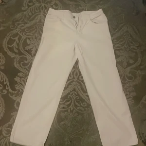 Vita raka byxor från Manfinity - Snygga vita byxor från Manfinity i rak modell. Byxorna har klassisk design med fickor fram och knappstängning. Tillverkade i en mix av bomull och polyester för en skön känsla och stilren look.