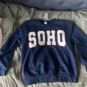 Marinblå sweatshirt med tryck från Lindex. - Marinblå sweatshirt från Lindex med tryck framtill. Tröjan har rund hals, ribbade muddar och är tillverkad i en mjuk bomullsblandning med ekologisk bomull. 