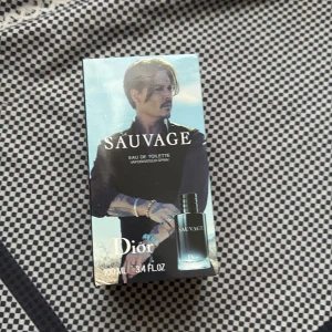 Dior Sauvage Eau de Toilette 100ml - Dior Sauvage Eau de Toilette 100ml i snygg förpackning med blå och svarta toner. Flaskan har en stilren, mörk design och parfymen är känd för sin fräscha och maskulina doft. Perfekt för dig som gillar exklusiva och trendiga dofter.