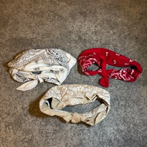 3 bandana i olika färger - Tre snygga bandana i vitt, rött och beige med klassiskt paisleymönster. Perfekta för att ge din look en cool touch. Knytning framtill ger en avslappnad vibe. Passar både till utsläppt hår och uppsatt. Man kan knyta upp också!