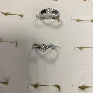  925 Silverpläterade Strass Par Ringer  - Fyra stilrena silverfärgade ringar, två med gnistrande stenar i klassisk solitärdesign och två med flera små stenar i rad. Perfekta för att mixa och matcha, med både släta och dekorerade band. Ger en elegant och modern vibe till din look.  155kr/ par , helt ny 