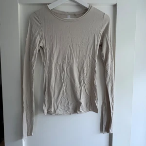 Beige långärmad topp från Kay/day - En basic beige långärmad topp från Kay/day i mjuk bomull. Tight passform med rund halsringning, perfekt att styla med jeans eller kjol. Enkel och stilren design som funkar året runt.