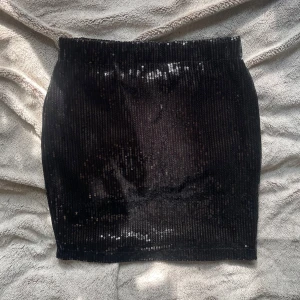 Svart paljettkjol från Jestoms - Supersnygg svart minikjol från Jestoms, täckt med glittriga paljetter som är perfekt till fest. Kjolen har en rak och tight passform. Elastisk midja.