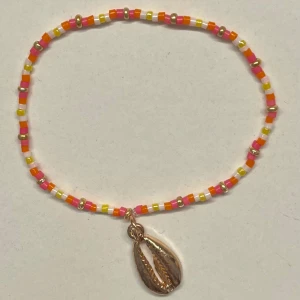 Färgglatt pärlarmband med snäckberlock - Hemgjort armband med små pärlor i rosa, orange, gult och vitt och en guldig snäckform. Jättegullig inför sommaren! Gjort med elastisk tråd och kan såklart göras i andra storlekar och färger💞💞                                                                  Obs! -guldpärlorna kan tappa sin färg om de tvättas mycket i vatten