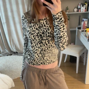 Leopardmönstrad kofta med knappar - Säljer en snygg leopardmönstrad kofta med svarta knappar framtill. Koftan är croppad och har lång ärm, perfekt för dig som vill sticka ut lite extra. Mjuk och skön att bära, passar till både jeans och kjol.