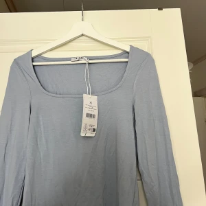 Ljusblå långärmad topp  - Supersnygg ljusblå långärmad topp från NA-KD med fyrkantig ringning. Tillverkad i mjukt och tunt material som känns skönt mot huden. Helt ny med prislapp kvar. Köpt på NAKD