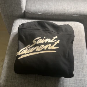Svart Saint Laurent hoodie S -  Tjena! Jag säljer nu min svarta hoodie från Saint Laurent. Varan är i 9,5/10 ett strykjärn hade inte skadat men utöver det så är den mint, äkthetsbevis medföljer vid köp. Priset är inte hugget i sten. Men inga skambud då detta är den mest eftertraktade hoodien från ysl mvh.