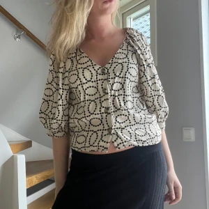 Trekvartsärmad blus - Superfin beige blus från H&M med svarta prickar i ett coolt mönster. Blusen har v-ringning, trekvartsärmar med lätt puff och knappar framtill. Perfekt till jeans eller kjol för en trendig look. Hör av dig vid frågor🤩