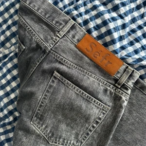 Grå straight jeans från Séfr - Snygga grå jeans från Séfr i rak modell. Jeansen har klassisk femficksdesign, silverfärgad knapp och läderpatch med logga bak. Tillverkade i italienskt denimtyg som ger en cool, tvättad look. Perfekta för dig som gillar stilrena och tidlösa jeans. Nypris 2500kr. W30L32