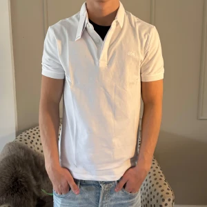 Lacoste Piké - Helt ny vit Lacoste piké i storlek Small, aldrig använd, modellen är 177 och väger 63 kg, skriv för minsta lilla fundering! 