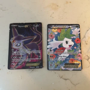 Pokémon EX-kort: Espeon EX & Shaymin EX - Två coola Pokémon EX-kort: Espeon EX med mörk, mystisk design och Shaymin EX med färgglad blomsterbakgrund. Perfekt för samlare eller dig som vill boosta din lek med unika och kraftfulla kort. Skapa din egen Pokémon-legend!