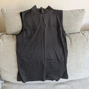 Svart polotopp från Peppercorn  - Svart och lite glittrig ärmlös polotopp med tight passform från Peppercorn. Jag är ca 170 cm för referens. Vid köp av flera klädesplagg av mig samfraktar jag såklart!