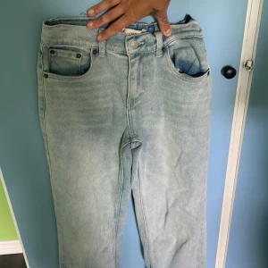 Levi's ljusblå loose fit jeans - Säljer ett par ljusblå jeans från Levi's med loose fit och klassisk femficksdesign. Jeansen har hög midja och raka ben, tillverkade i slitstarkt denim. Perfekta för dig som gillar en avslappnad och trendig look. Tyvärr är loggen i bak borta.