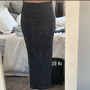 Svart långkjol med tight passform - Säljer en svart långkjol med hög midja och tight passform. Kjolen är enkel och stilren, perfekt att matcha med crop tops eller oversized tröjor. Materialet känns mjukt och följsamt mot kroppen.