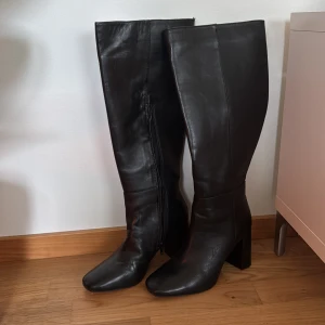 Svarta höga stövlar från NA-KD - Svarta stövlar från NA-KD med fyrkantig tå och bred klack. Dragkedja på insidan. Använda 1 gång så i bra skick