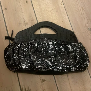 Svart paljettväska från Ray BEAMS - Unik svart kuvertväska från Ray BEAMS med glittriga paljetter och croc-mönstrade handtag. Väskan har en cool form och dragkedja upptill. Perfekt för dig som vill sticka ut med en statement-accessoar. Köpt i Japan<3
