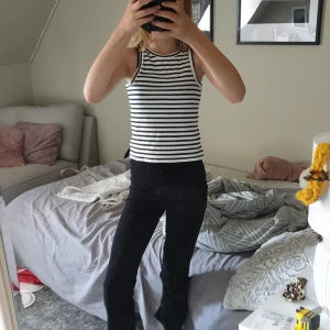 Randig ribbad linnetopp - Snygg ärmlös linnetopp med svarta och vita ränder. Toppen är ribbad och har en tight passform med rund halsringning. Perfekt för en chill och stilren look.