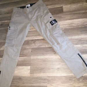 Beige cargopants från Calvin Klein Jeans - Snygga beige cargopants från Calvin Klein Jeans med stora fickor på sidorna och tydlig CK-logga. Byxorna har skinny passform och är gjorda i bomull. Perfekta för en avslappnad och trendig look.