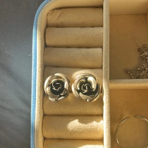 Silverfärgade rosformade örhängen - Säljer ett par örhängen i form av rosor i silverfärg. De har en tydlig blomdesign och är perfekta för dig som gillar unika accessoarer med romantisk känsla. Passar till många olika stilar och tillfällen.
