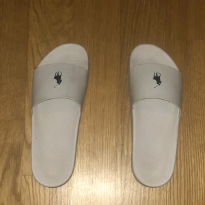 Nästan helt nya tofflor från Ralph lauren - Säljer vita tofflor från Ralph lauren, perfekt för sommaren. De är lite använda, några få gånger. Säljer för att jag letar efter något annat. Köp snabbt!
