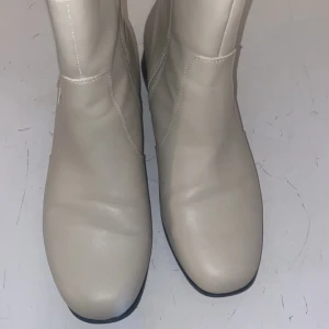 Beige chelsea boots i skinn - Säljer ett par stilrena beige chelsea boots från Wavy i skinn. Skorna har svart resår på sidorna och låg klack. Perfekta för dig som vill ha en klassisk look med modern touch.