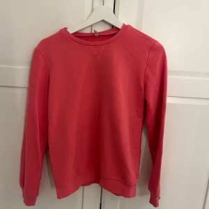 Rosa sweatshirt med rund hals - En enkel och stilren rosa sweatshirt med rund halsringning och långa ärmar. Perfekt för en avslappnad look och passar till det mesta. Mjuk och skön bomullskänsla. Liten i storleken 