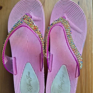Rosa sandaler med platåsula och strass - Säljer ett par rosa sandaler med platåsula och transparenta remmar dekorerade med färgglada strasstenar. Perfekta för dig som vill sticka ut med lite extra bling! Supersnygga till sommarens outfits.