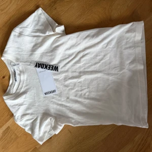 Vit t-shirt från Weekday - Säljer en oanvänd t-shirt från weekday, modellen är lite kortare och tajtare än en vanlig t-shirt. Storlek xs
