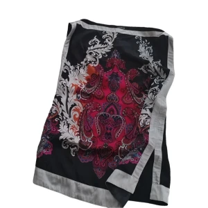 Mönstrad svart och röd siden blus från Bebe - Snygg blusen från Bebe i svart siden med röd och vit barockinspirerad mönsterdetalj. Blusen har ljusgrå kant och är perfekt för att ge din outfit en färgklick.