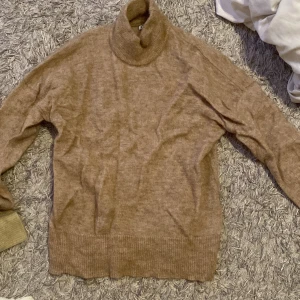 Beige polotröja i ullmix - Mysig beige polotröja med lång ärm och bred ribbad mudd vid ärmslut och nederkant. 