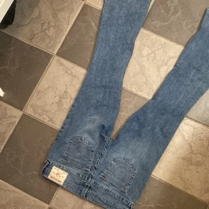 bootcut Jeans från True Religion - Säljer ett par klassiska blå bootcut jeans från True Religion med ikoniska bakfickor och tydliga sömmar i baby pink. Helt nya endast testade.