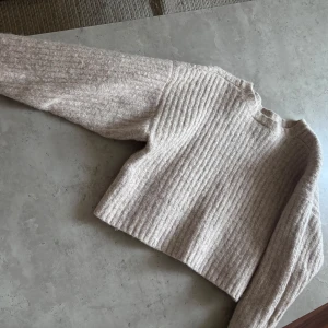 Beige croppad stickad tröja från Weekday - Säljer en beige croppad stickad tröja från Weekday. Tröjan har ribbat mönster, lång ärm och en lite boxig passform. Fint i skicket och superskön!!