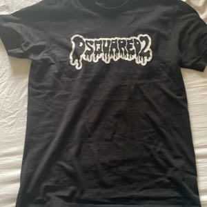 Svart t-shirt från Dsquared2 - Säljer en svart t-shirt från Dsquared2 med vit, droppande logotyp på bröstet. Klassisk passform och rund halsringning. Perfekt för dig som gillar streetwear och vill ha något stilrent men ändå med attityd.