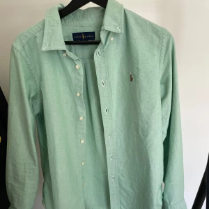 Ljusgrön skjorta från Ralph Lauren - En ljusgrön skjorta från Ralph Lauren i storlek 14/16 vilket motsvarar XS. Säljer pågrund av att den är för liten för mig. Inte använt mycket alls, så i bra skick.