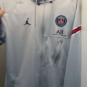 Grå PSG x Jordan zip-hoodie - Tja säljer denna helt nya psg hoodie, inga skador eller defekter som sagt helt ny skick 10/10, den är grå med snygga detaljer hör av er !