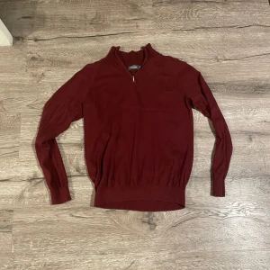 Vinröd Half-zip - Säljer en vinröd tröja med halv dragkedja i kragen. Tröjan har lång ärm och ribbade muddar vid ärmslut och nederkant. Perfekt för lager-på-lager och snygg till jeans eller chinos.