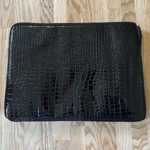 Svart datorväska med krokodil mönster  - Snygg svart datorväska med glansig krokodil design  och dragkedja. Insidan är mjuk och ljus för extra skydd till din laptop. Perfekt för att bära med sig datorn till skolan eller jobbet!💕💕 MÅTT: längd 36cm, bredd 26cm