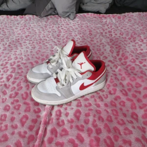 Nike Air Jordan 1 Low - Nike Air Jordan 1 Low sneakers i vitt, grått och rött. Storlek 4Y som motsvarar storlek 36💞de är i fint skick förutom lite smuts vilket jag ska försöka tvätta bort innan jag postar dem🫶🏻