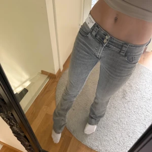 Grå bootcut jeans från H&M - Säljer ett par gråa bootcut jeans från H&M med låg midja och klassiska fickor både fram och bak. Jeansen har en snygg tvätt och är perfekta för dig som gillar en lite vidare passform nertill.