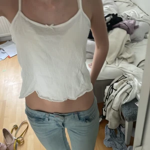 Vit croppad linnetopp - Säljer en enkel och stilren vit croppad linnetopp med tunna axelband och liten rosettdetalj framtill. Toppen har en lätt rynkad struktur och rak passform, perfekt till sommaren.från lager 157 i storlek S. I bra skick. Hör av dig om du har frågor eller funderingar 💕