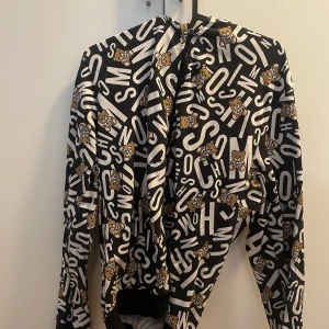Moschino hoodie  - Moschino hoodie som man sticker ut lite i mängden med. Sällsynt modell och säljs inte mera.                                                                                 Cond: 9/10                                                                      Flaws: Inga, förutom att snörerna till hoodie ej tillkommer.                                                                     Size M passar S.