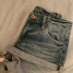 Mörkblå lågmidjade jeansshorts  - Snygga mörkblå jeansshorts med klassisk femficksdesign och upprullad kant. Shortsen har synliga sömmar i kontrastfärg och knappstängning framtill. Perfekta för en avslappnad stil. Lappar bortklippta (men väldigt säker på strl xs) o tyvärr för små för mig.